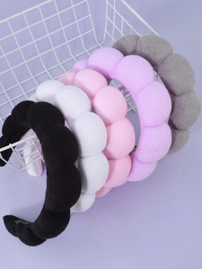 Detailed view of cloud-shaped sponge headbands in five soft colors in a white basket