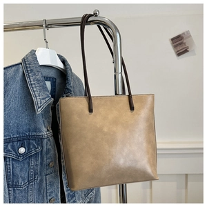 Detail view of a brown faux leather tote bag hanging on a minimalist silver metal hanger