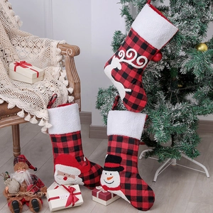 Three Christmas stockings with Santa, snowman and elk figures on red and black plaid fabric