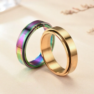 Detail of spinning spinner rings in gold and rainbow colors on elegant beige backdrop