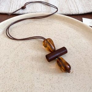 Macro detail of amber resin pendants on a brown cord over a cream ceramic plate