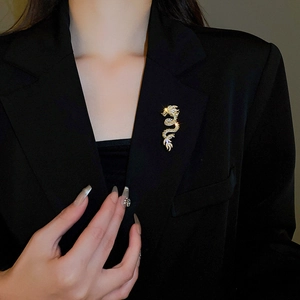 Detailed view of a sparkling gold dragon brooch with white rhinestones on black lapel