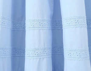 Détail du tissu en coton bleu clair avec une broderie raffinée en dentelle florale