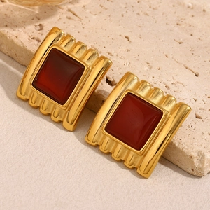 Macro shot of gold-plated square stud earrings featuring deep red synthetic rubies