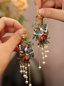 Détail de boucles d'oreilles vintage papillon et grenade avec glands en perles et émail