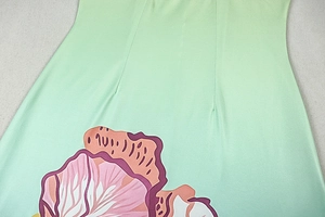 Detail view of smooth gradient green fabric with artistic floral prints on long dress