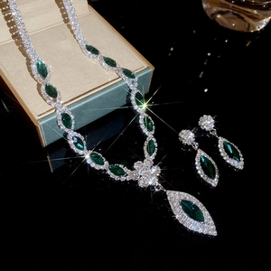 Detailed view of luxury silver flower jewelry set with green gems in a gift box