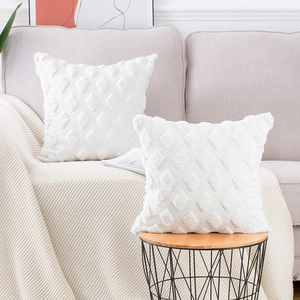 Close-up of two white plush pillow covers with diamond pattern on a sofa and side table