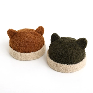 Close-up of cozy lamb wool baby hats with cute animal ears in brown and dark green