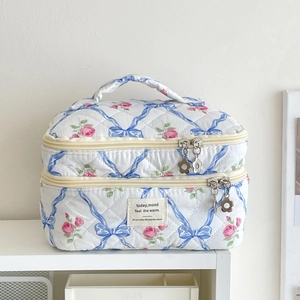 Détail de la trousse de maquillage à fleurs avec roses, nœuds et tirette fleurie