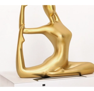 Detailed close-up of golden yoga sculpture with matte metallic finish on book