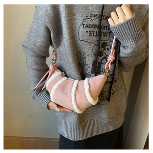 Detailed close-up of pink crescent bag featuring white faux shearling stripes and gold rings