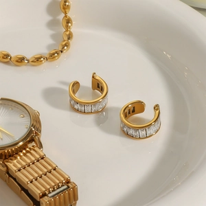 Gold-tone C-shape ear cuff with rectangle cubic zirconia stones on white ceramic tray
