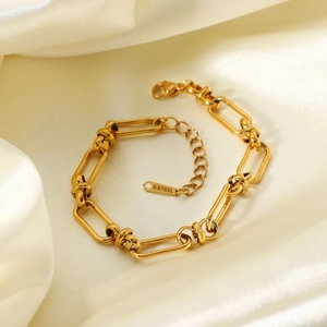 Macro shot of 18K gold plated wide chain bracelet on beige silk background