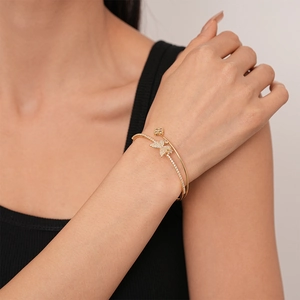 Close-up of golden double-layer open bangle featuring zircon butterfly and clover motifs