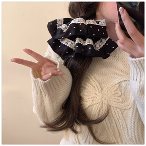 Close-up of a retro polka dot scrunchie with white lace edge worn on a ponytail