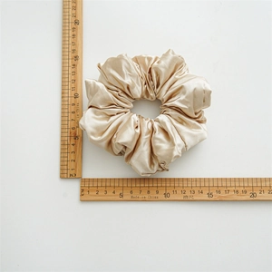 Detailed view of large champagne silk scrunchie with 12cm diameter scale measurement