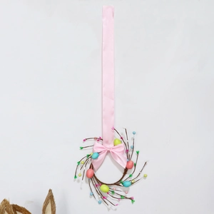 Detail of Easter wreath with colorful eggs, berries, and a long pink silk ribbon bow
