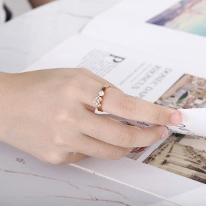 Close-up of rose gold honeycomb ring with diamond accent on hand over marble background