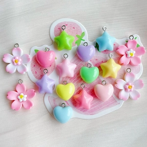 Flat lay of colorful resin heart, star, and flower charms with metal loops for DIY jewelry