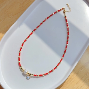 Détail du collier mauvais œil avec perles rouges, perle d'eau douce et pendentif