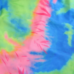 Macro shot showing vibrant pink, blue, and lime green tie-dye fabric texture on summer dress