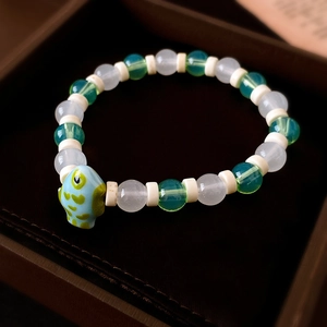 Nahaufnahme eines Perlenarmbands mit hellblauem Fisch-Anhänger in einer edlen Schmuckdose