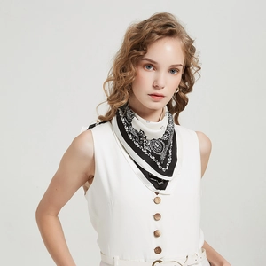Detail of a silk-feel square scarf with black and white paisley print on a female model