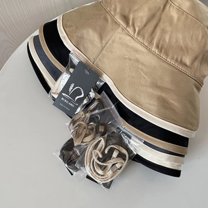 Close-up of stacked cotton bucket hats in khaki and black with adjustable chin straps