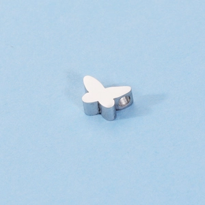 Macro shot of mirror-polished stainless steel butterfly charm with small hole for DIY jewelry