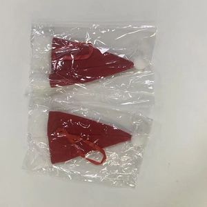 Gros plan de deux mini bonnets de Noël rouges en tissu emballés dans des sacs plastiques