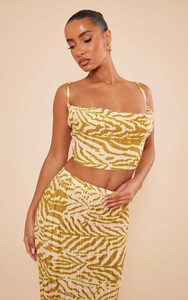 Detailed view of yellow zebra print pleated fabric on a two-piece crop top and midi skirt