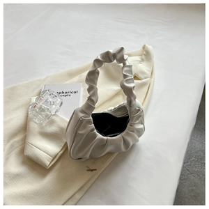 Top view of a white ruched underarm bag with zipper on a beige blazer background