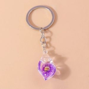 Macro detail of a resin conch keychain featuring a purple gradient and tiny natural seashell