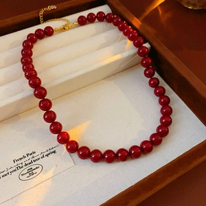 Close-up of vintage red beaded necklace with golden heart pendant on a wooden box