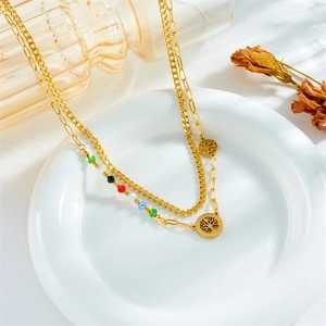 Detail of double-layer gold chain bracelet with colorful beads and Tree of Life charms