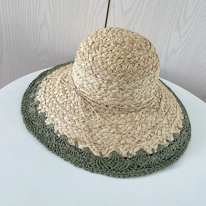 Détail d'un chapeau de soleil en raphia tissé main avec bord ondulé vert et nœud