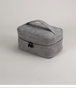 Detailed view of gray fabric vanity bag featuring top handle and dual metal zippers
