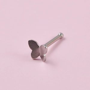 Macro detail of silver stainless steel butterfly nose stud with straight bar and ball end