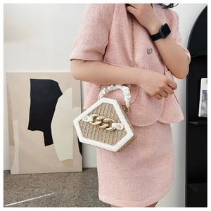 Detail view of hexagonal straw handbag with gold chain and white leather trim on model