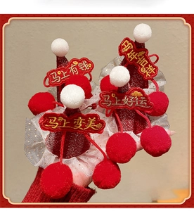 Close-up of festive red sequin hair clips with white pom-poms and Chinese embroidery