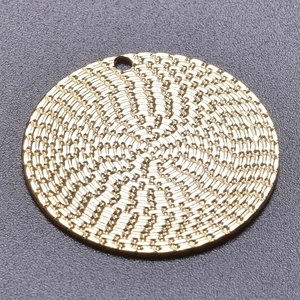 Macro shot of 18k gold plated round pendant with detailed woven texture for DIY jewelry