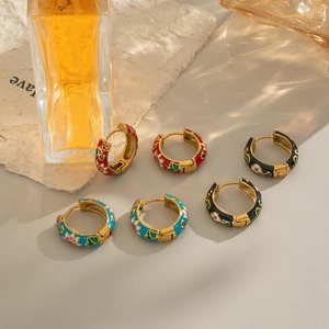 Detailed close-up of gold-plated stainless steel hoop earrings with colorful enamel floral motifs
