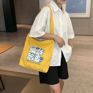 Detail of yellow canvas tote bag with rabbit illustrations and text print for students