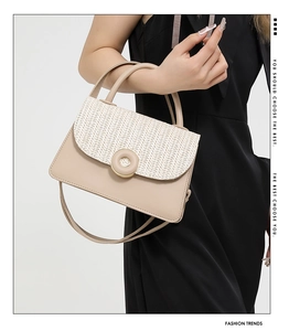Detail of beige square handbag featuring woven straw texture and round metal buckle lock