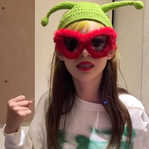 Detail of red plush heart-shaped sunglasses with stylish cat eye frame and green fuzzy trim