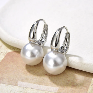 Detail of elegant silver drop earrings featuring large polished white pearls and hooks