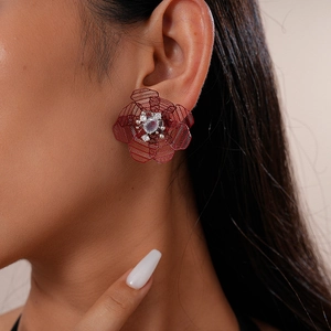 Detail shot of vintage hollow mesh red flower earrings with central sparkling gemstone
