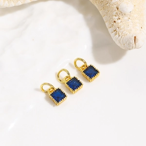 Detail of square blue zircon charms with 18k gold plating on a natural conch