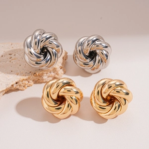 Detailed view of gold and silver knot earrings on a decorative stone base